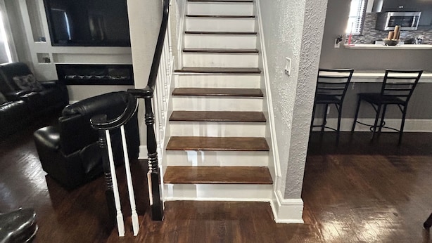 A staircase leading to a loft bedroom with a view of the sky, a dining area with a kitchen in the background, and a living room with a TV and seating. - Arched Haven (Newark)