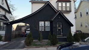 A two-story house with a black front porch, a garage, and a driveway. - Arched Haven (Newark)