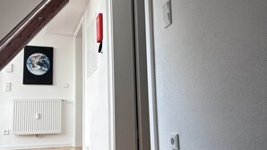 A staircase leading to a landing with a radiator and a framed picture on the wall. - 247 Reside: Apartment SZ3 | Center | Netflix (Straubing)