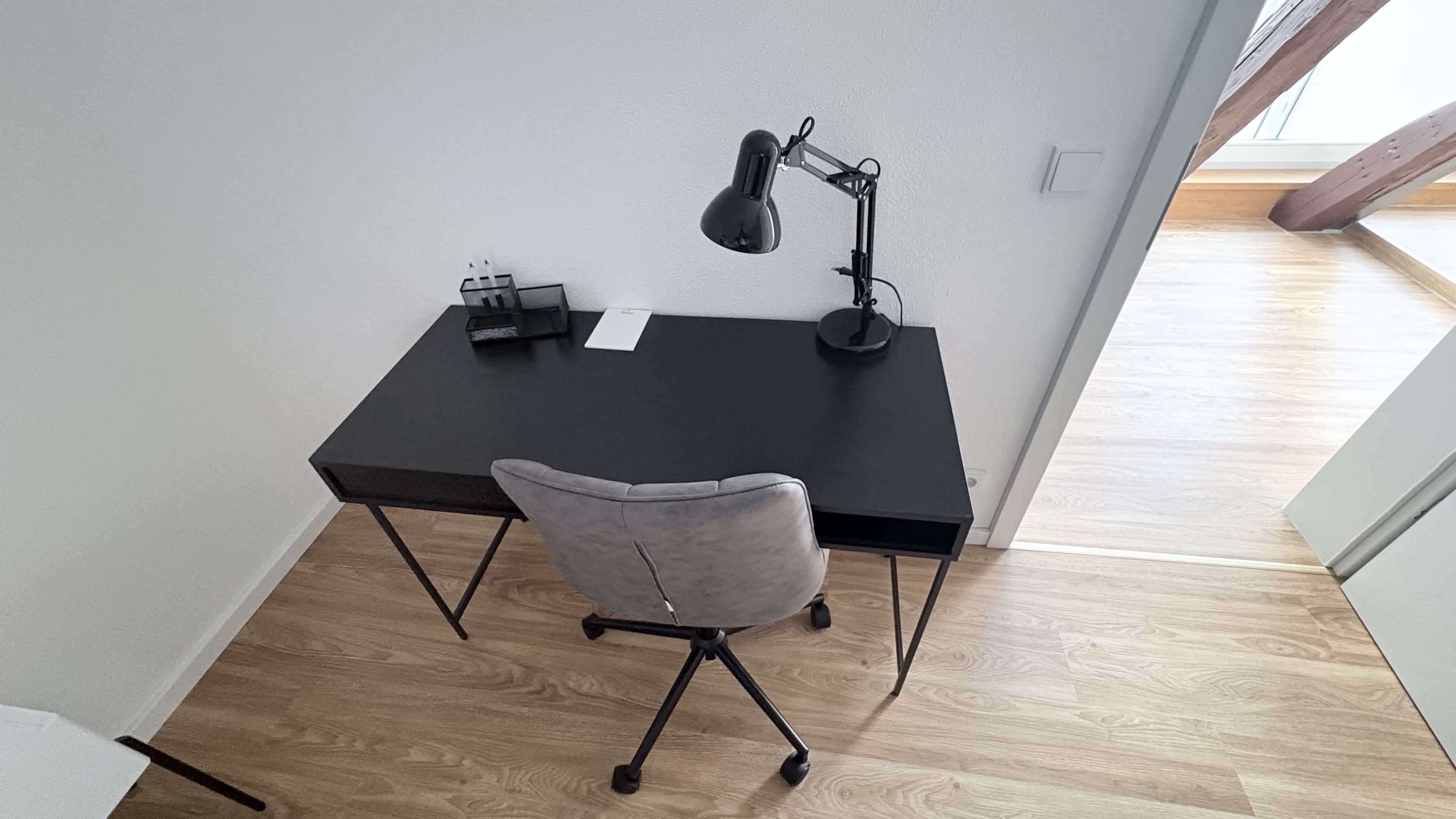 Een compacte, moderne werkplek met bureau, stoel en bureaulamp.
