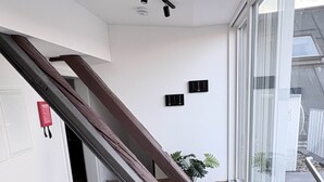 A modern interior with a wooden floor, a staircase, a large window, and a ceiling with track lighting. - 247 Reside: Apartment SZ3 | Center | Netflix (Straubing)