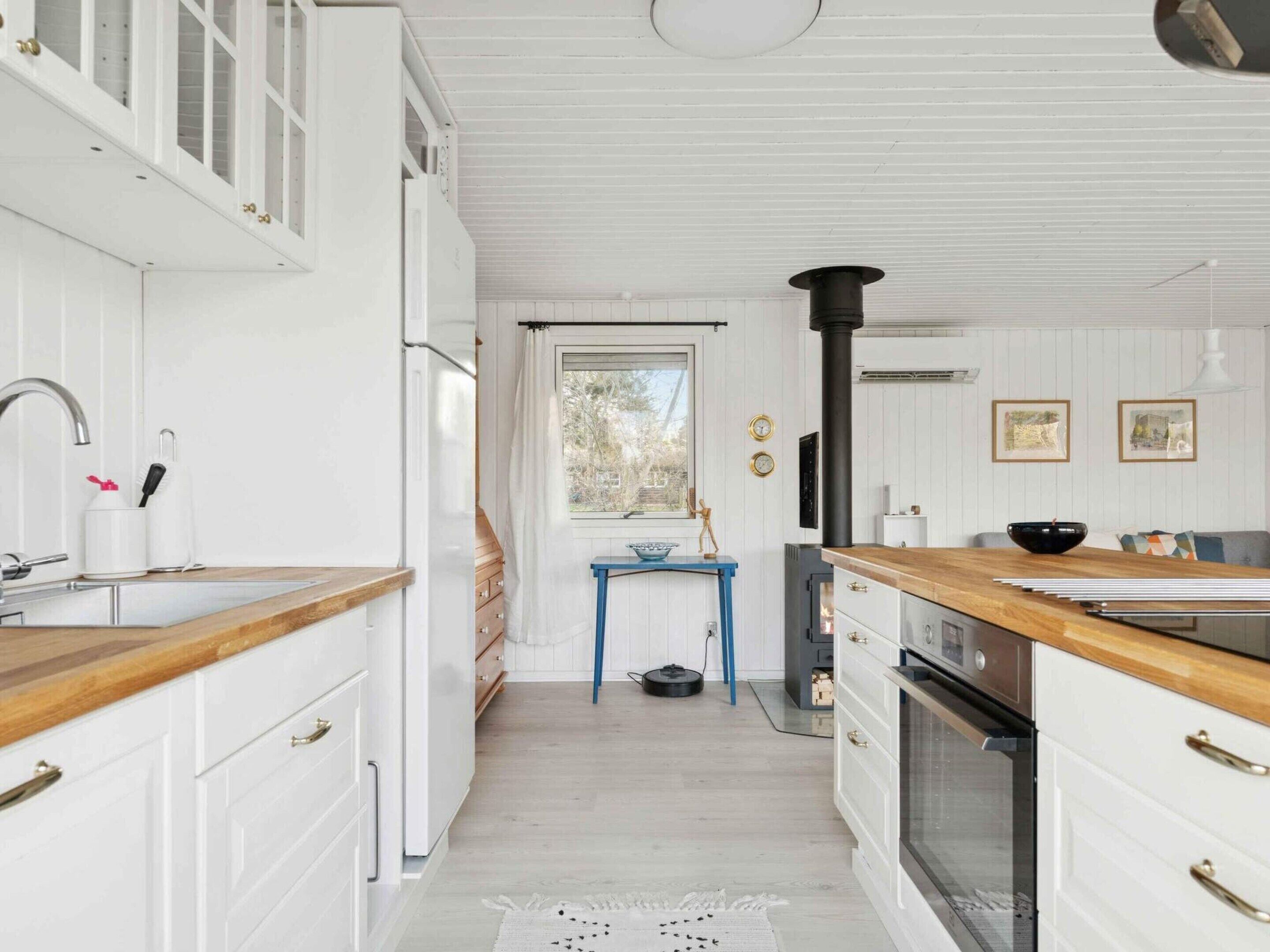 A kitchen with white cabinetry, a wooden countertop, a stove, and a blue table.