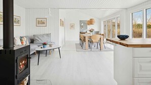 A modern interior with a fireplace, dining area, and large windows. - 4 Star Holiday Home in Vaeggerlose (Vaeggerlose)