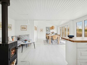 A modern interior with a fireplace, dining area, and large windows. - 4 Star Holiday Home in Vaeggerlose (Vaeggerlose)