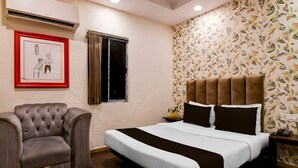 Un dormitorio con cama, una silla, un ventanal y una pared con estampado floral.