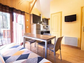 Una habitación con cama, una mesa de comedor con sillas, una kitchenette, un televisor y una puerta.