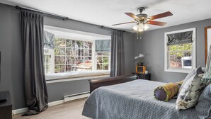 A bedroom with a bed, a ceiling fan, a window with curtains, and a view of trees outside. - Modern 2BR Near Gillette Stadium • Private Yard (Sharon)
