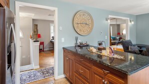 A kitchen with a clock, wooden cabinets, and a countertop with various items. - Modern 2BR Near Gillette Stadium • Private Yard (Sharon)