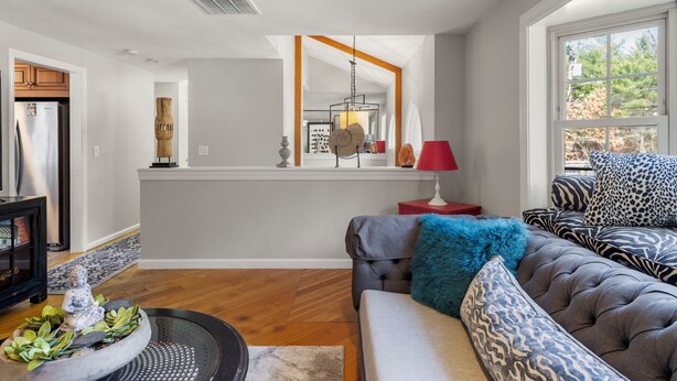 A modern living room with a sofa, a red lamp, and a large window. - Modern 2BR Near Gillette Stadium • Private Yard (Sharon)
