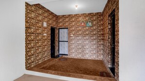 Una habitación con paredes de ladrillo estampado, una puerta y un ventanal pequeño con diseño floral.