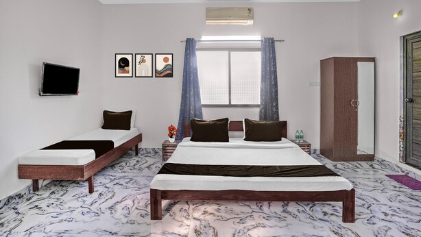 Un dormitorio con cama, televisión, armario y ventana con cortinas.