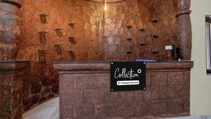 Un área de recepción con pared de piedra, lámpara colgante y señalización de servicios ofrecidos por la empresa.