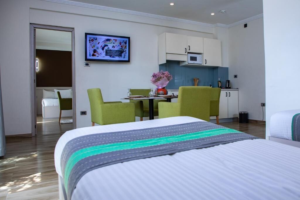 Een hotelkamer met een bed, een bureau met stoelen, een televisie, een magnetron en een kitchenette.