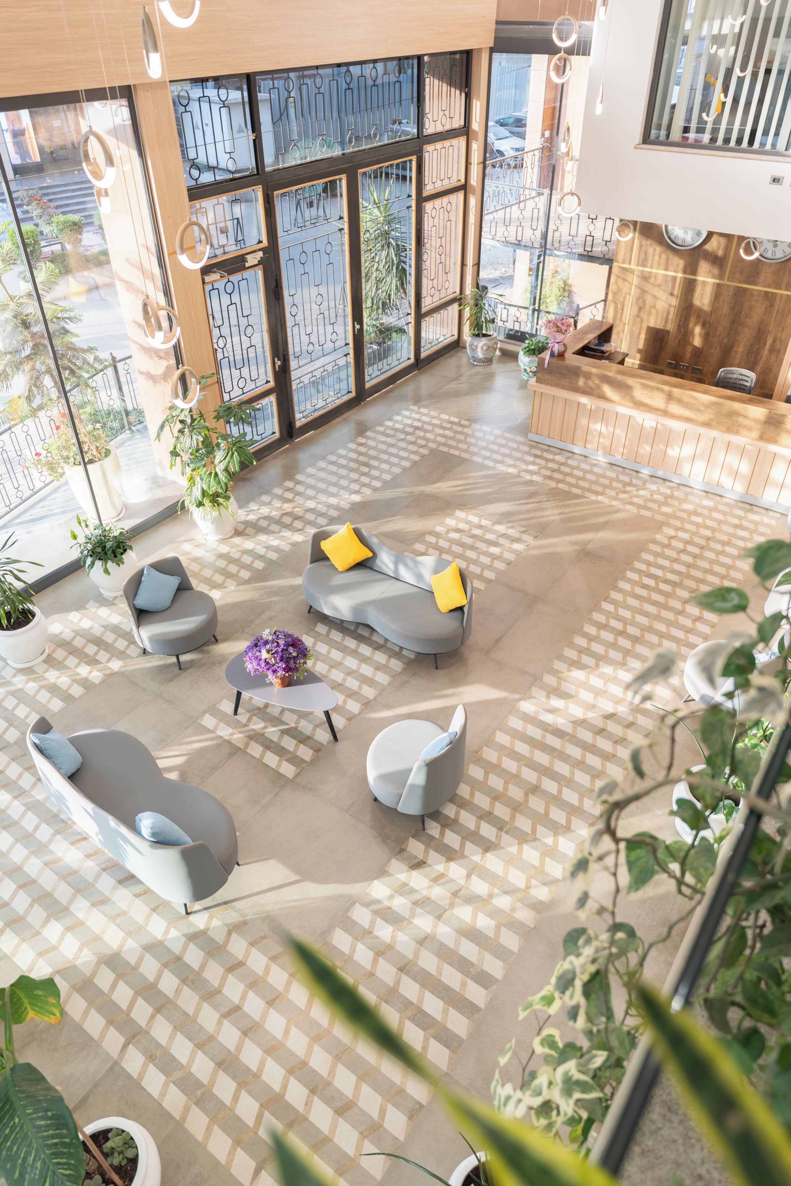 A spacious lobby with a checkered floor, seating areas, and potted plants.