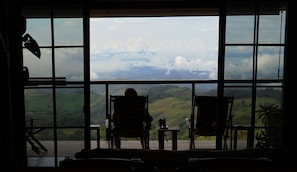 A room with large windows, a chair, and a table.