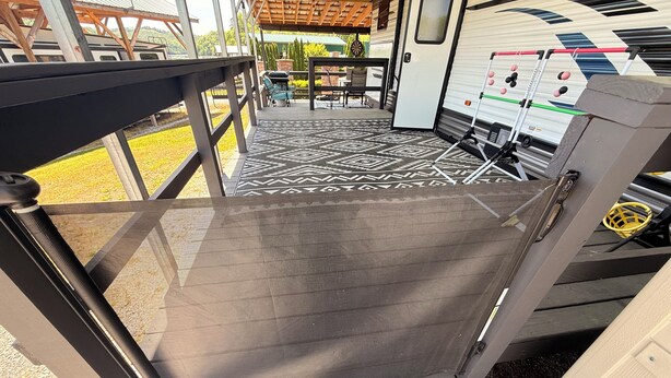 A covered outdoor area with a metal railing, a patterned floor, and a table with chairs. - Wake&Lake at Norris Landing Marina-Waterfront RV Retreat with Deck + Slip Option (Tazewell)