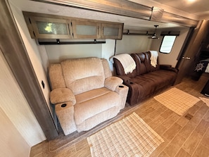 A compact RV interior with a sofa, a small table, and a window.