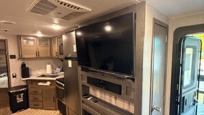 A compact kitchen with a flat-screen TV, built-in oven, and a small refrigerator. - Wake&Lake at Norris Landing Marina-Waterfront RV Retreat with Deck + Slip Option (Tazewell)