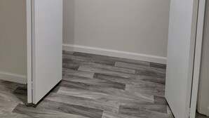 Un vestidor con piso de espiga gris, paredes blancas y una barra metálica para colgar ropa.