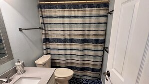 Un baño con lavamanos, inodoro y cortina de ducha blanca.