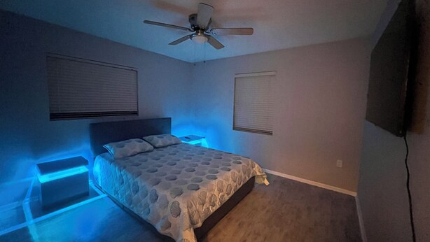 Un dormitorio con cama, ventilador de techo e iluminación empotrada.
