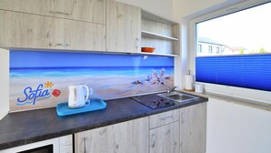 A kitchen with a beach-themed backsplash, a coffee maker, and a window with blinds. - Two-story Holiday Homes With a Summer Pool (Postomino)