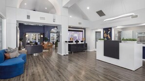 Eine geräumige Lobby mit einer Rezeption, einer Sitzecke und einer modernen Küche im Hintergrund.