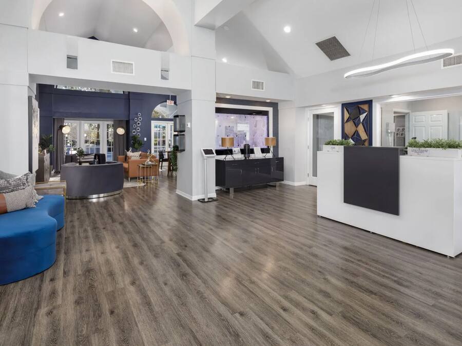 A spacious lobby with a reception desk, seating area, and a modern kitchen visible in the background.