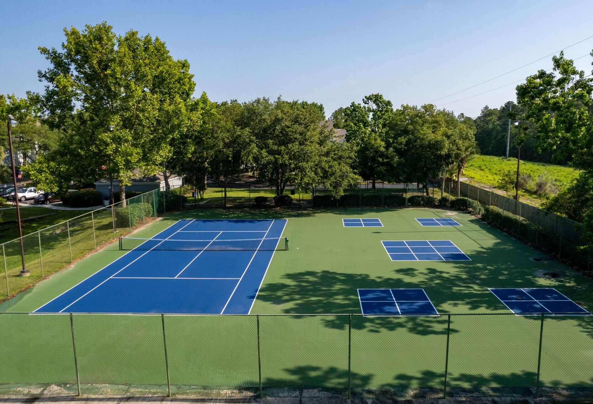 Ein Außen-Tennisplatz mit mehreren Plätzen, umgeben von Bäumen und einem...