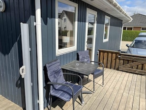 A deck with a table and chairs, a wooden fence, and a house in the background. - 4 Star Holiday Home in Borkop (Borkop)