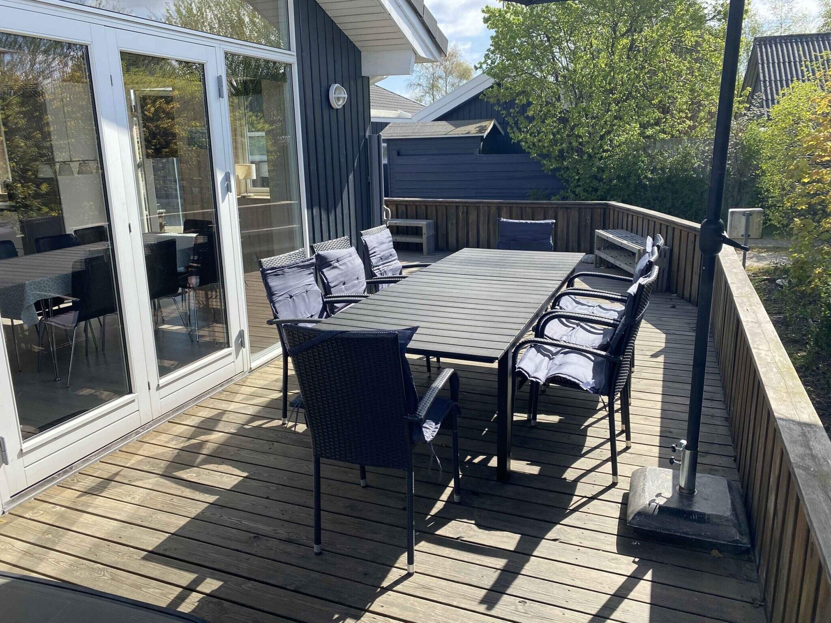 Eine Terrasse mit Tisch und Stühlen, einer Glastür und einem Holzzaun.