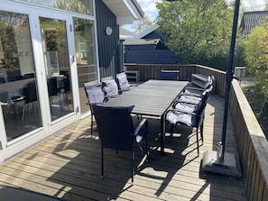 A deck with a table and chairs, a sliding glass door, and a wooden fence. - 4 Star Holiday Home in Borkop (Borkop)