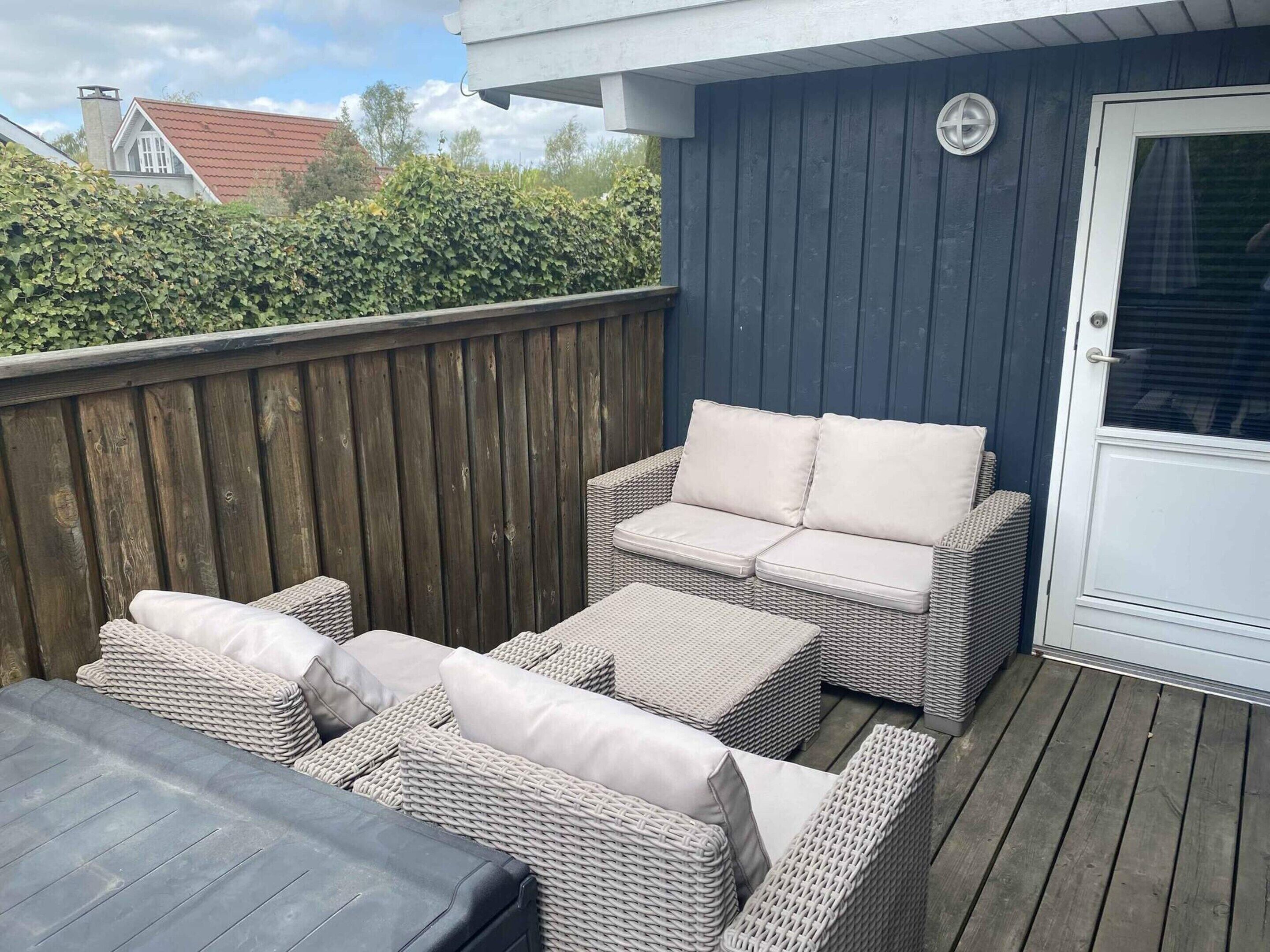 A covered outdoor seating area with wicker furniture and a door.