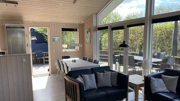 A spacious room with a wooden ceiling, large windows, a dining area, and a sofa. - 4 Star Holiday Home in Borkop (Borkop)
