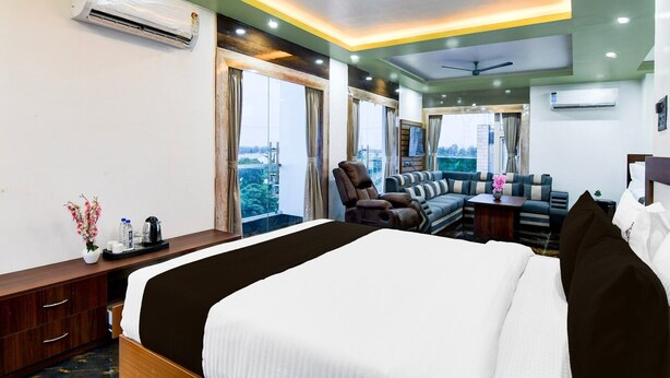 Habitación de hotel con una cama grande, un sofá, una silla, un escritorio y vistas a la ciudad.