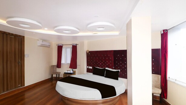 A bedroom with a bed, wooden flooring, a ceiling with recessed lighting, a wardrobe, and a window with curtains. - Super Deluxe Room Bank More Dhanbad (Dhanbad)