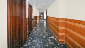 A hallway with wooden doors, a tiled floor, and a white ceiling. - Super Deluxe Room Bank More Dhanbad (Dhanbad)