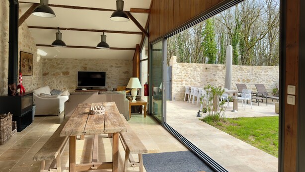 A spacious living area with a wooden table, a television, and a stone wall.