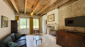 A living room with a sofa, a table, a fireplace, and a TV mounted on a stone wall.