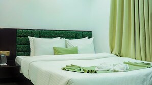 A modern hotel room with a large bed, a headboard with a green pattern, a bedside table with a phone, and a curtain on the window. - Sylhet Regency Ltd. (Sylhet)