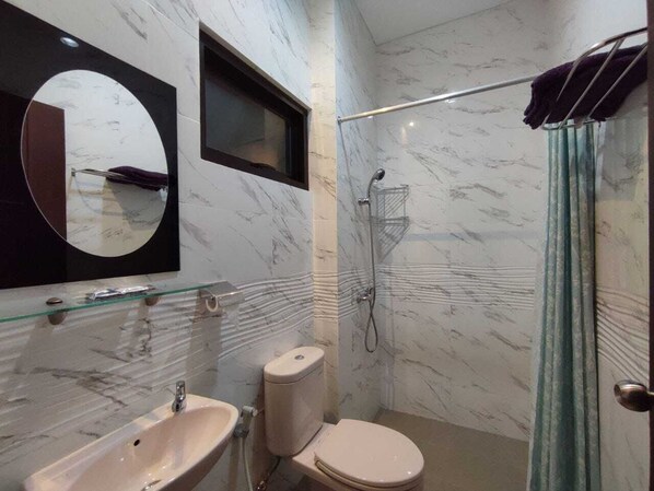 A bathroom with a marble wall, a glass shelf, a toilet, and a shower. - Nirvana House (Guest House Syari'ah) (Salatiga)