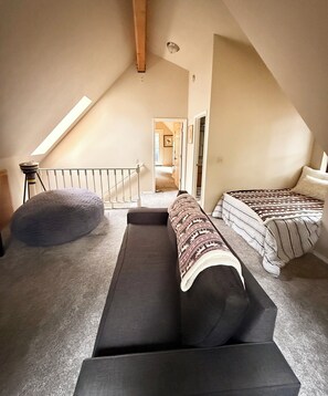 A loft bedroom with a high ceiling, a skylight, a staircase, and two beds. - Hamilton branch Creekside Cabin in the Trees (Westwood)