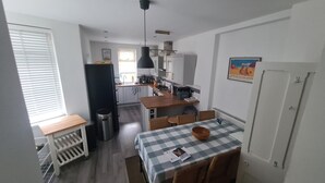 Una cocina compacta con comedor, un cubo de basura y una ventana con persianas.