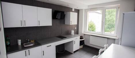 A modern kitchen with white cabinets, a black countertop, a window with a view, and a built-in microwave.