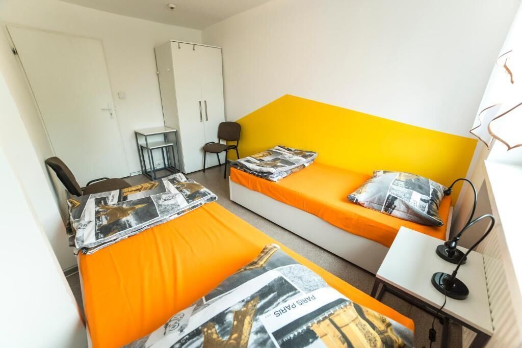 Een kamer met twee bedden, een bureau, een stoel en een kledingkast.