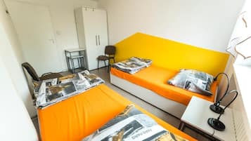 Una habitación con dos camas, un escritorio, una silla y un armario.