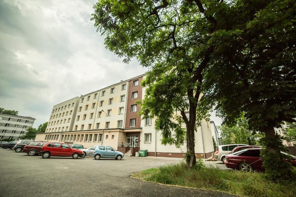 En bygning med flere etager og en parkeringsplads foran.