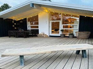 A covered outdoor area with a wooden deck, a bench, and a table. - 4 Star Holiday Home in Albaek (Jerup)