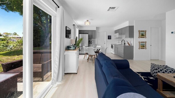 A modern living room with a sofa, dining area, and kitchen. - Fisherman's Cottage - 2 bd/1 bath apartment in Naples park! Close to beaches! (Naples)