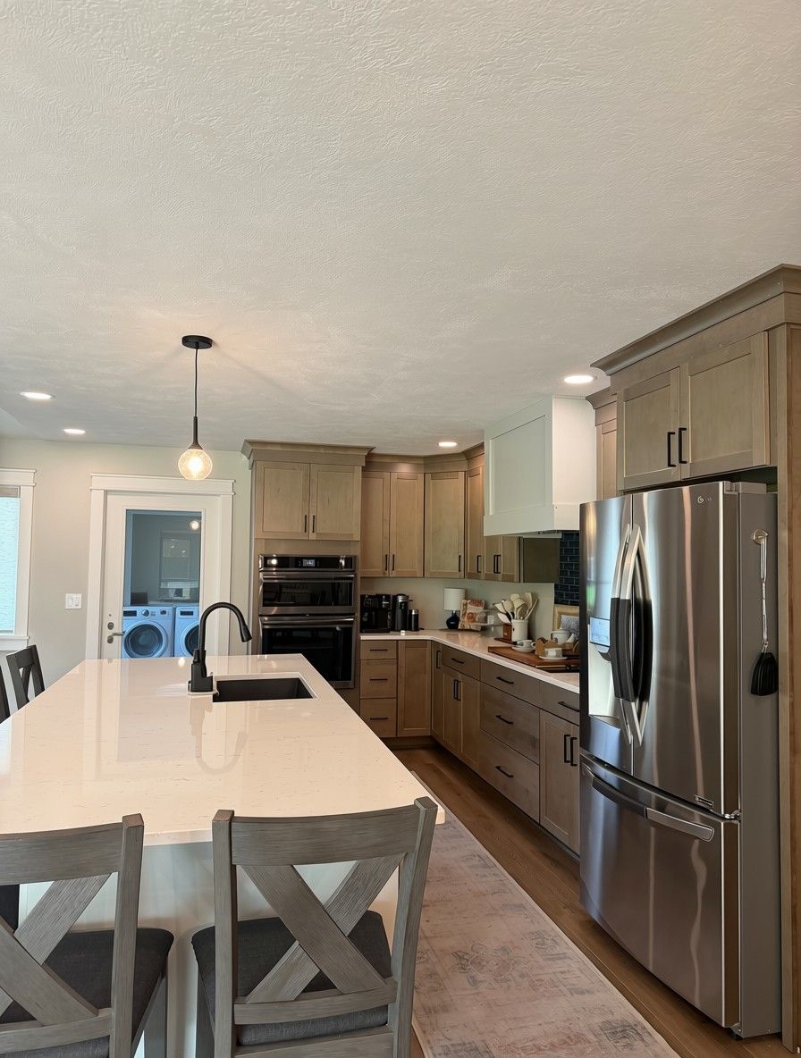 A modern kitchen with a central island, stainless steel appliances, and wooden cabinetry.